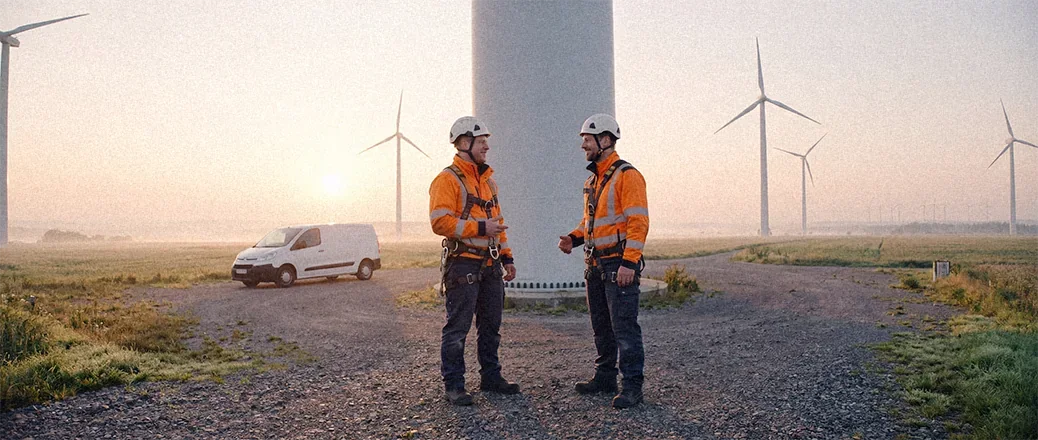 Zwei Windkrafttechniker im Gespräch vor einer Windenergieanlage