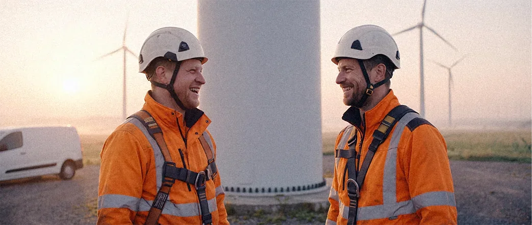 Cinematisches Portrait zweier Windkrafttechniker in orangefarbener Arbeitskleidung
