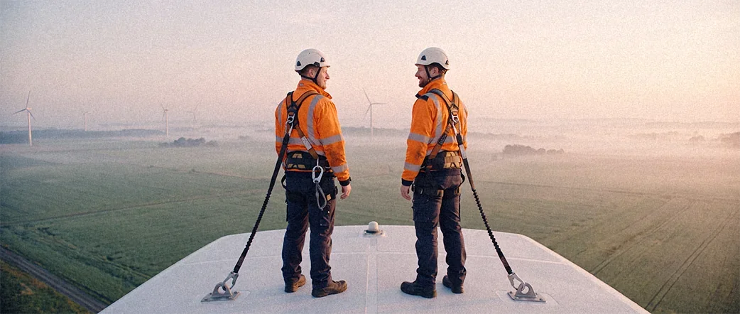Zwei gesicherte Techniker stehen auf der Gondel eines Windrads